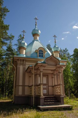 Yükseliş Şapeli Spaso-Preobrazhensky Valaam Stavropegic Manastırı. Yeşil ormandaki mavi kubbeli ahşap şapelin dikey fotoğrafı.