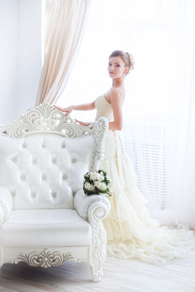 Young bride near curtains.