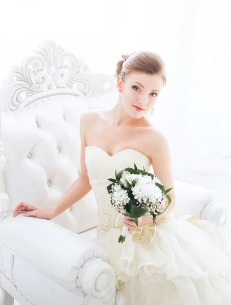 Junge Braut sitzt in einem Sessel mit Blumen. — Stockfoto