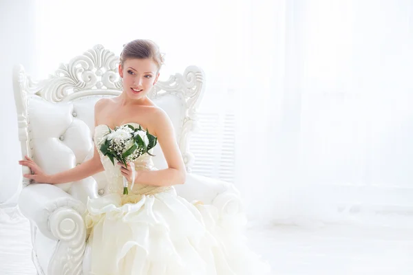 年轻的新娘坐在扶手椅上用鲜花. — 图库照片