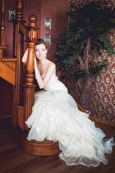 Noiva em vestido de noiva é sobre as escadas no interior . — Fotografia de Stock
