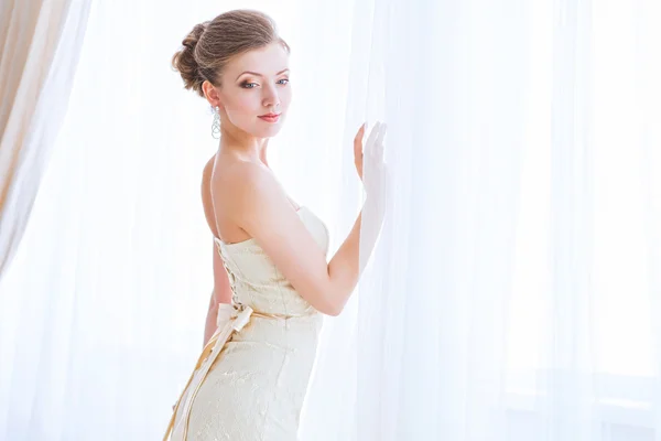 Bela noiva aguardando seu marido perto de cortinas . — Fotografia de Stock