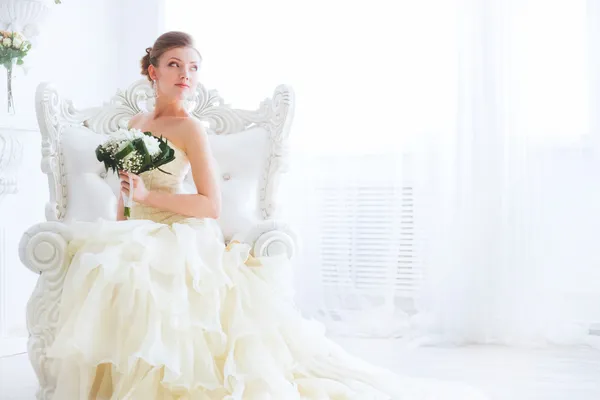 Young bride is sitting in an armchair with flowers. — Stock Image Young bride is sitting in an armchair with flowers. Stock Photo