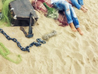 kot pantolon, erkek ve kadın ile bir valiz, ekoseli battaniye kum plaj üzerinde yatarken bacaklarını açıp mesh, zincir ve buket, güneşli trendy vintage tarzı görüntü çapa