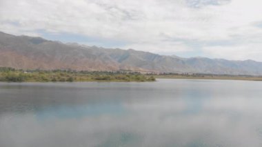Yüksek dağların arka planına karşı güzel bir göl. Sabahın erken saatlerinde bir turkuaz göl üzerinde insansız hava aracı uçuşu. Kırgızistan 'daki Alp Gölü Issyk-Kul.