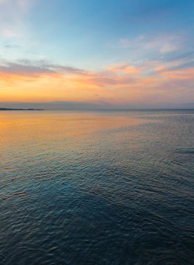 Gün batımında denizin üzerinde renkli bulutlar