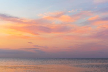 Gün batımında denizin üzerinde renkli bulutlar