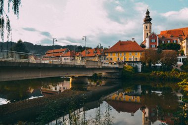Avusturya 'nın sonbahar şehrinde nehrin üzerinde güzel bir köprü. Nehrin karşısındaki dağlarda köprü.