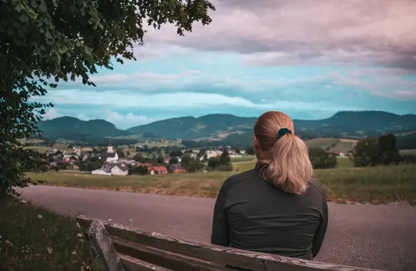 A woman sits on a bench and rests. Nature and mountains in Austria, hiking in the mountains.