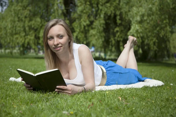 Russian girl with book on the grass in the park Royalty Free Stock Images