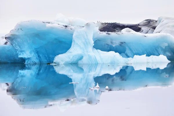 Blue iceberg symmetrically reflected in the water — Stock Photo, Image