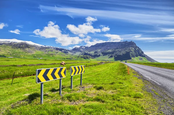 Icelandic landscape with green fields, mountains and road signs — Stock Photo, Image