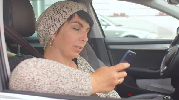 Joyful woman uses phone before date. She reads message from phone screen.