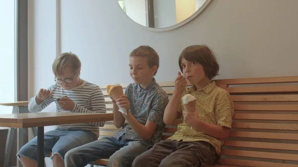 Группа подростков сидит на скамейке в кафе. Они едят мороженое.. — стоковое фото