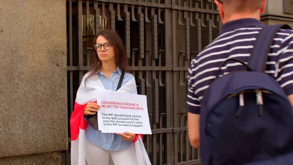 Vrouw houdt een poster handen in de buurt van administratieve gebouw Rode witte vlag schouders — Stockfoto