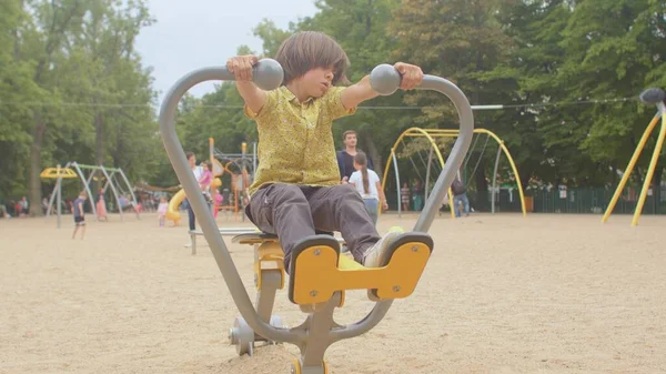 Ein aktiver Kerl trainiert den Waffensimulator Stadtpark. Er zieht und drückt den Körper — Stockfoto