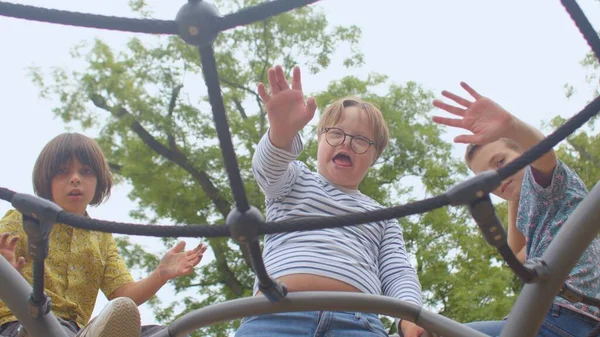 The boys wave to the camera affably. A child with glasses has Down syndrome. — Stock Photo, Image