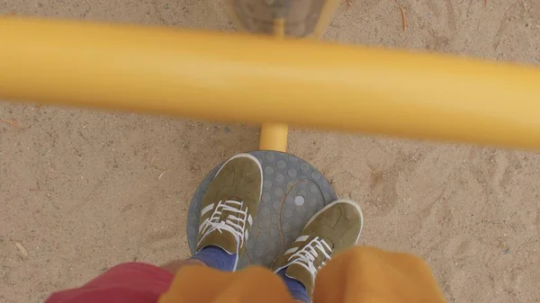 The legs man in sneakers do leg rotation exercise on the simulator. — Stock Photo, Image