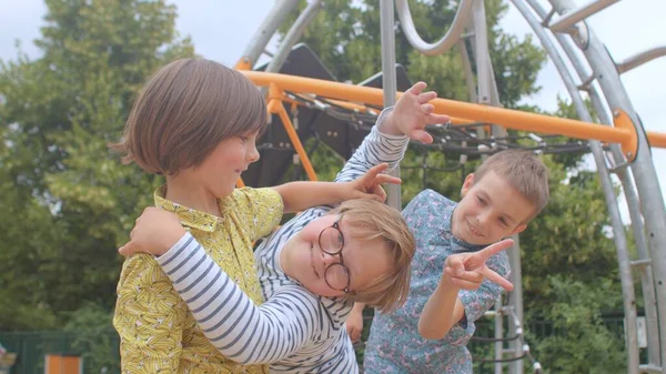 Vrolijk gezelschap tieners hebben plezier op de speelplaats. Ze grimmelen, maken hoorns.. — Stockfoto