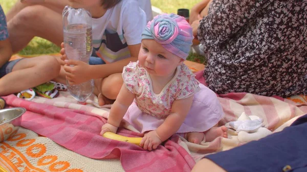 Menina tentando pegar uma banana no piquenique. Bebê de 6 meses aprendeu a sentar — Fotografia de Stock