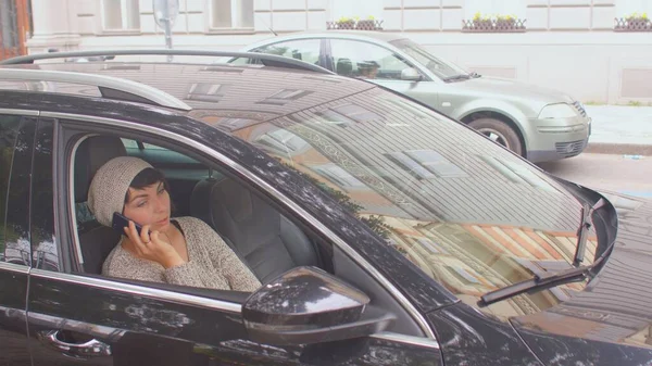 Žena v klobouku mluví po telefonu v autě. Je to pasažér. — Stock fotografie