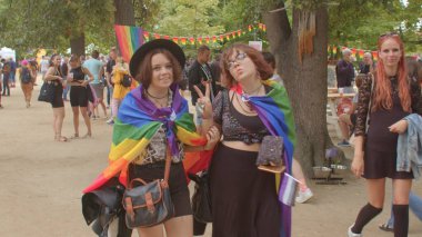 Şehir parkındaki LGBT geçit töreninde iki kişi. Bir jest yapıyor, tanıştığımıza memnun oldum.