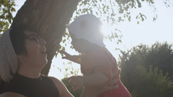 Kobieta z dzieckiem na wsi. Mama całuje dziecko, natura kocha, słoneczny dzień. — Zdjęcie stockowe