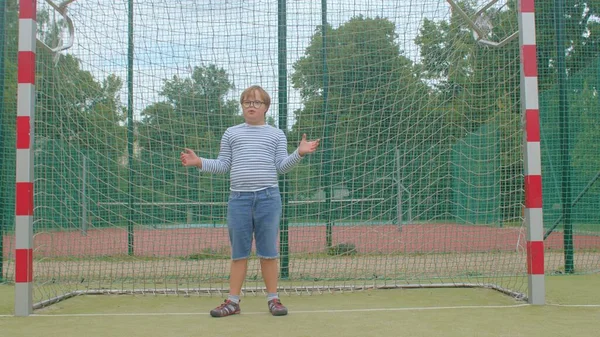 Down syndrom chlapec s brýlemi stojí v cíli fotbalu. — Stock fotografie