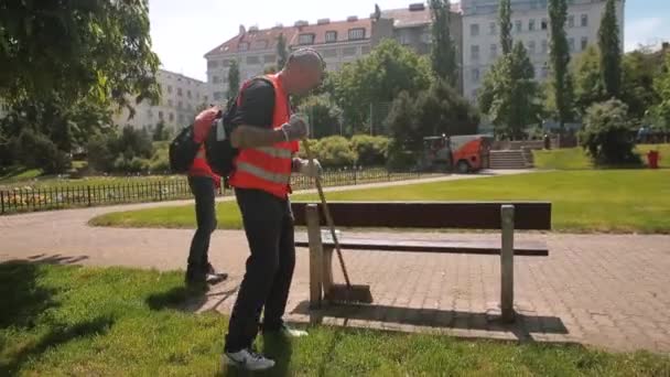 Workers camera movement. Street cleaning city park. Workers sweep ground brushes — Stock Video