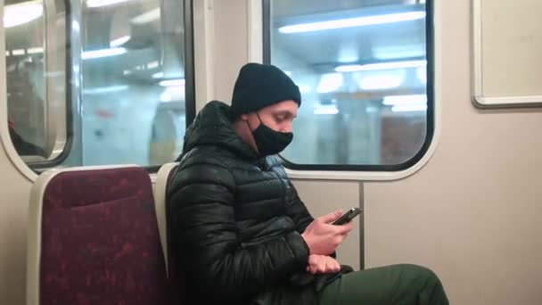 Un homme masqué est assis à la fenêtre du train. Il utilise le téléphone. Vérification des notifications. — Video