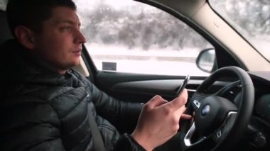 Telefonla araba kullanan bir adam dikkati dağılmış. Telefon ekranına bakıyor..