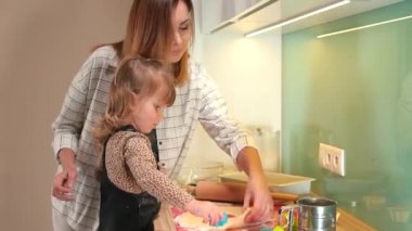 Anne ve kızı mutfakta kurabiye yapıyor. Hamurda bir yıldız şekli oluştururlar.