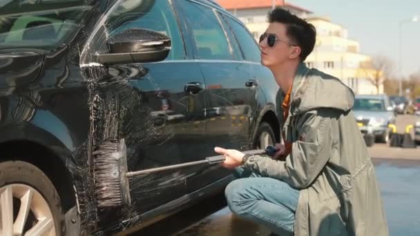 A lusta ember lassan mossa a kocsit száraz kefével. Megdörzsöli a festéket. — Stock videók