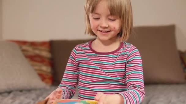 Radość z używania ekologicznej zabawki w domu dziewczyna otwiera puzzle na stole. — Wideo stockowe