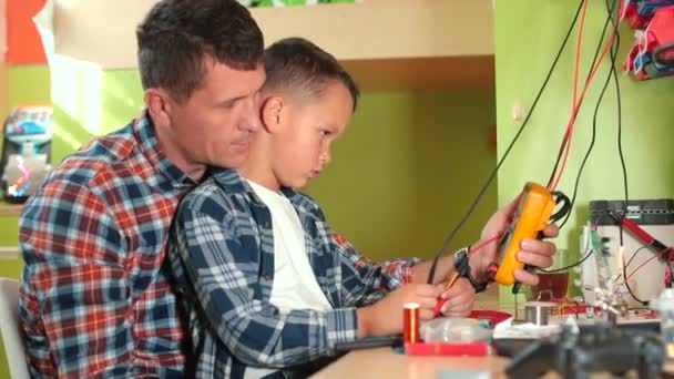 Vater und Sohn nutzen Stromtester. Sie verbinden die Drähte, um Daten zu kontrollieren. — Stockvideo