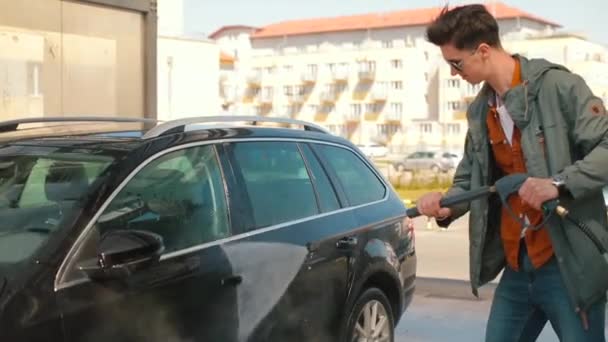 Mannen tvättar bilen med händerna med jetvatten han applicerar skyddande lager bil — Stockvideo