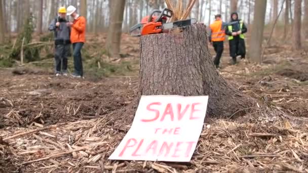 La motosierra está sobre un tronco de árbol. Hay siguiente cartel para Salvar el Planeta. — Vídeo de stock