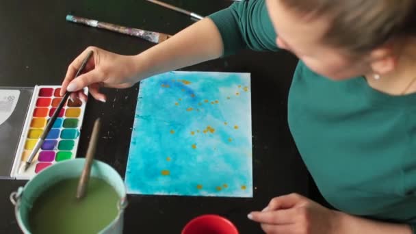Женщина художественная школа делает акварельную живопись Она использует метод распыления краски бумаги — стоковое видео