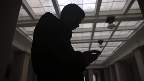 Silhouette man använder telefonen i händerna. Han skannar innehåll på telefonskärmen — Stockvideo