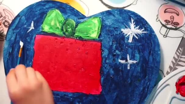 Twee handen maken één kunstwerk. Afbeelding van een rood pakje met cadeau, groene strik. — Stockvideo