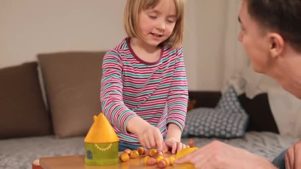 Le professeur enseigne à l'enfant à mettre des morceaux en pot. Acquérir une nouvelle habileté motrice fine. — Video