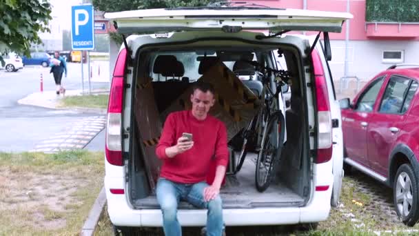 Muž sedící v kufru auta mluví na video linkovém telefonu se zákazníkem. — Stock video