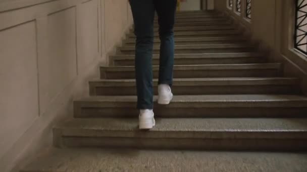Muž v bílých botách stoupat po schodech budovy. Přesunutí návštěvníka na vyšší úroveň — Stock video