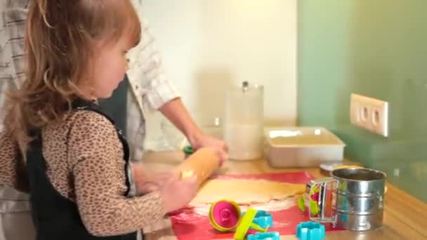 Мама выкатывает тесто, дочь держит запеканку. Печенье на домашней кухне. — стоковое видео