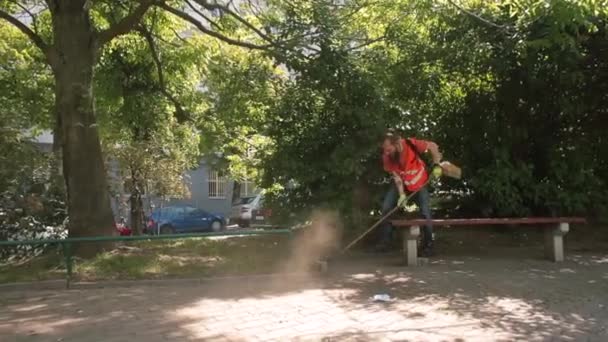 Het proces van het reinigen van de stoep in het stadspark. Distributiewerkzaamheden. — Stockvideo