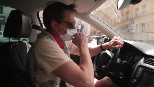 Maskovaný muž kašle, když řídí auto dech čerstvý vzduch po nošení masky. — Stock video