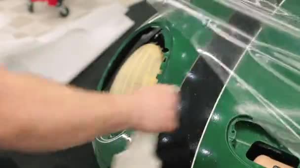 Un trabajador aplica la solución a la carrocería del coche para pegar vinilo de polímero. — Vídeos de Stock