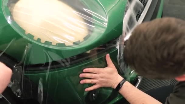 Ręce mechanika trzymać ochronną warstwę winylu na farbie modułu samochodu. — Wideo stockowe