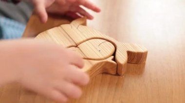 Çocuk elleri ahşap bulmacayla oynuyor. Ekolojik materyaller kullanıyor. Dokunsal pedagoji..