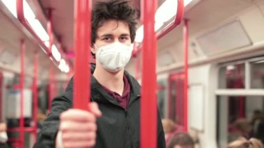 Maskeli adam metro tırabzanlarını tutuyor. Solunum korumalı toplu taşıma aracı.